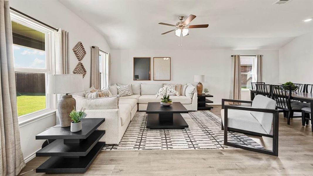 This spacious living area features light-colored flooring, white walls, and a ceiling fan, creating an inviting atmosphere