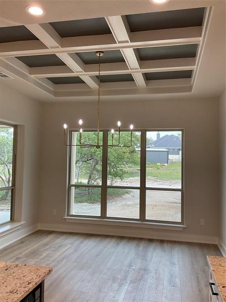 Dining room with tray ceiling and custom box beam treatment. Wall of windows provides loads of natural light in this space.