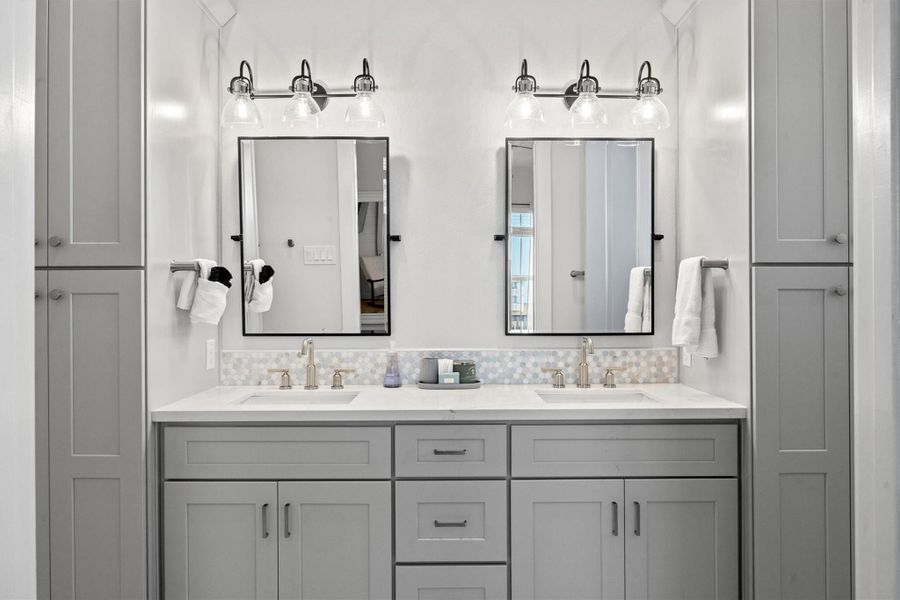 The primary ensuite features a dual vanity with elegant quartz countertops, two tall linen closets for ample storage, and a design that enhances the coastal vibe of the space.