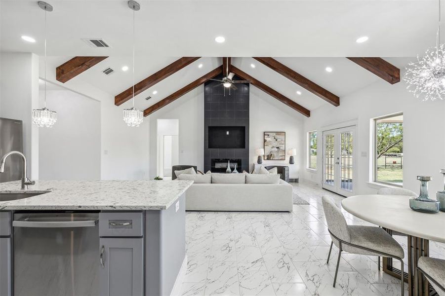 Kitchen featuring ceiling fan with notable chandelier, light tile patterned flooring, stainless steel dishwasher, hanging light fixtures, and sink