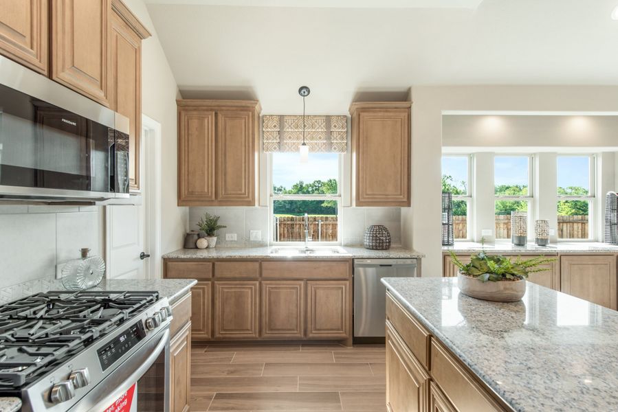 Kitchen with light wood cabinets, granite countertops, and stainless steel appliances including gas range and dishwasher