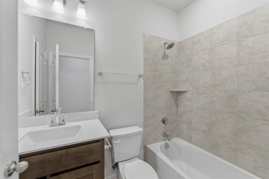 Modern bathroom featuring a wood-finish vanity with a white countertop and integrated sink, chrome faucet, and rectangular mirror
