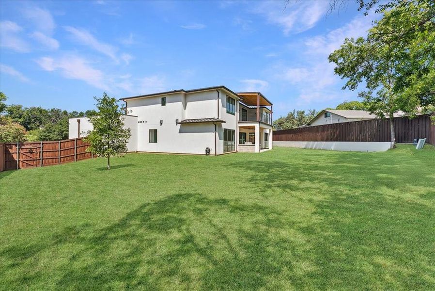 Back of house featuring a fenced backyard, a patio area, a balcony, and stucco siding