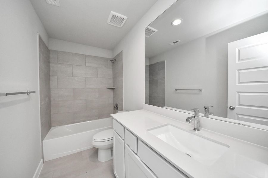 Secondary bath features tile flooring, bath/shower combo with tile surround, light stained wood cabinets, beautiful light countertop. Secondary bath features tile flooring, bath/shower combo with tile surround, light stained wood cabinets, beautiful light countertop.