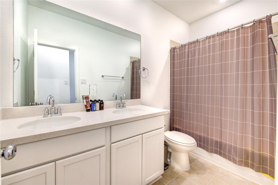 Shared Bathroom that is shared between the Third and Fourth Bedroom, features high ceilings with recessed lights, double vanities with ample cabinet and storage space, and a tub-shower combo.