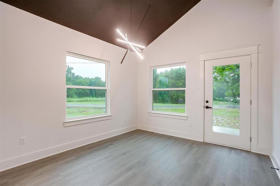 Empty room featuring wood finished floors and vaulted ceiling