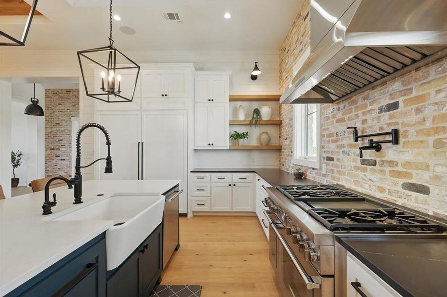Kitchen featuring wall chimney exhaust hood, stainless steel appliances, white cabinets, decorative light fixtures, and recessed lighting Kitchen featuring wall chimney exhaust hood, stainless steel appliances, white cabinets, decorative light fixtures, and recessed lighting