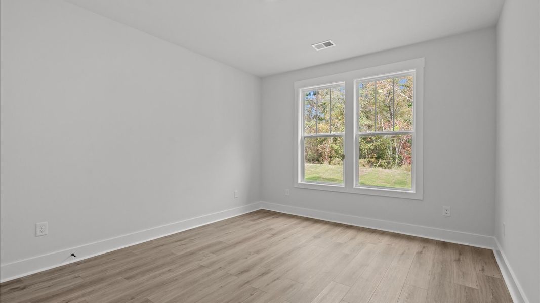 Thoughtfully designed secondary bedrooms featuring hardwood flooring and tasteful detail