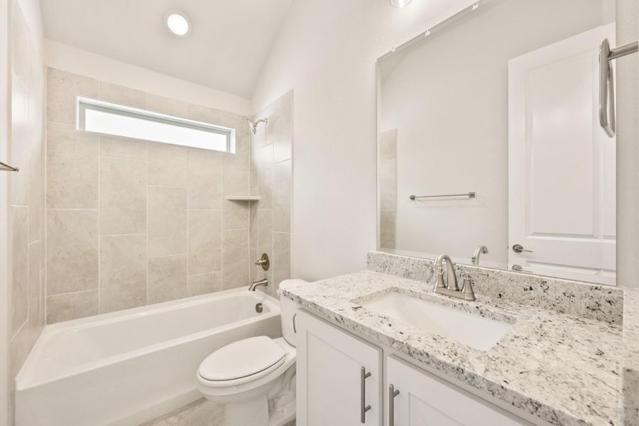 Bathroom with granite vanity, white cabinets, and tiled tub-shower combo with small window Bathroom with granite vanity, white cabinets, and tiled tub-shower combo with small window