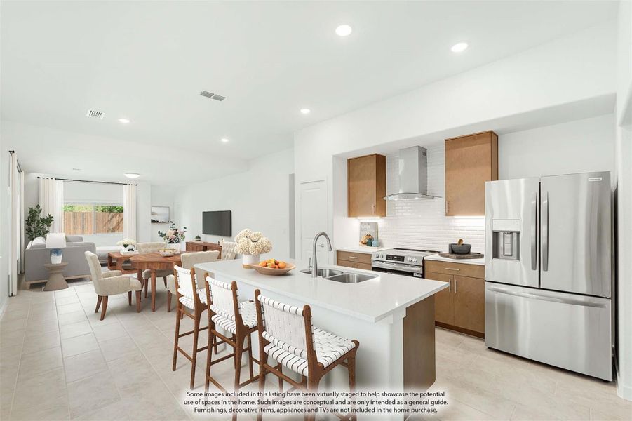 Open-plan kitchen with white island, wood cabinets, stainless appliances, and dining and living areas beyond.