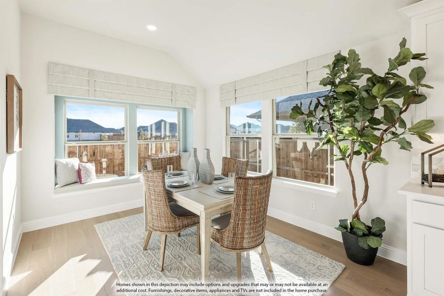 Bright dining area with wicker chairs, wood table, window seat, and large windows with natural light