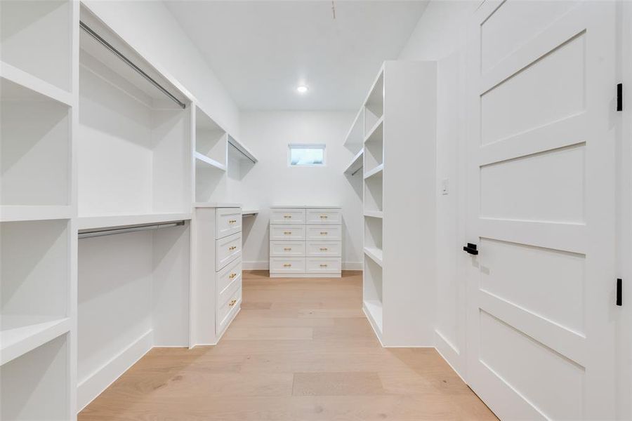 Massive walk-in primary closet featuring custom built-ins, abundant shelving, and drawer storage for optimal organization.