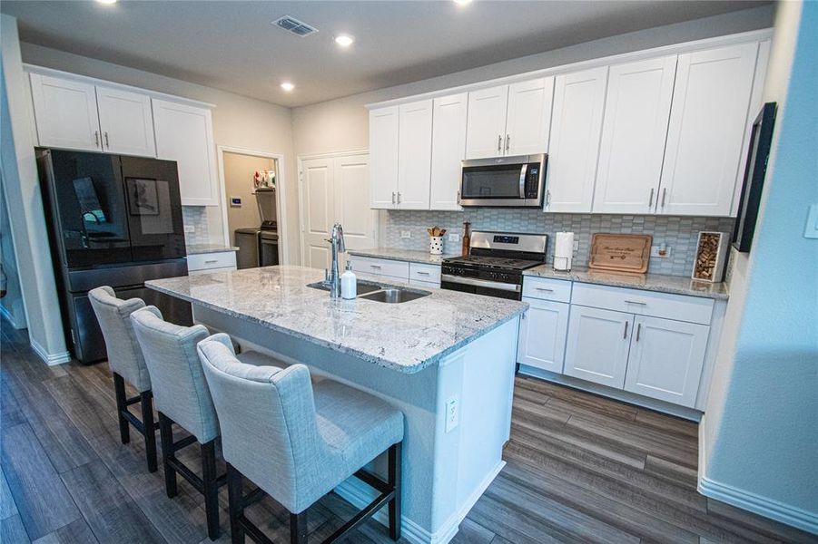 Kitchen featuring white cabinetry, stainless steel appliances, decorative backsplash, light stone counters, and recessed lighting Kitchen featuring white cabinetry, stainless steel appliances, decorative backsplash, light stone counters, and recessed lighting