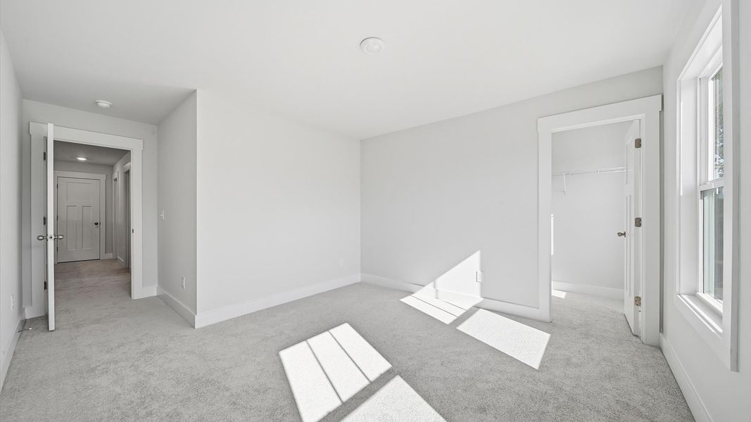 Superior comfort in this light-filled bedroom with plush carpeting and thoughtfully placed large windows at Creeks at Midway