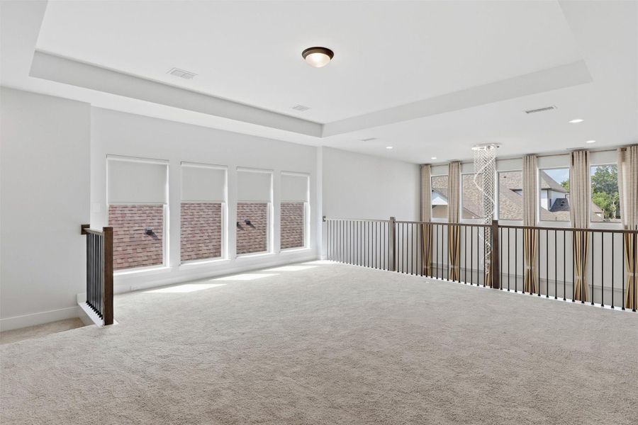 The expansive upstairs game room offers endless flexibility for a media lounge, playroom, home gym, or additional living space. A tray ceiling, plush carpeting, and abundant natural light create a bright and welcoming atmosphere.