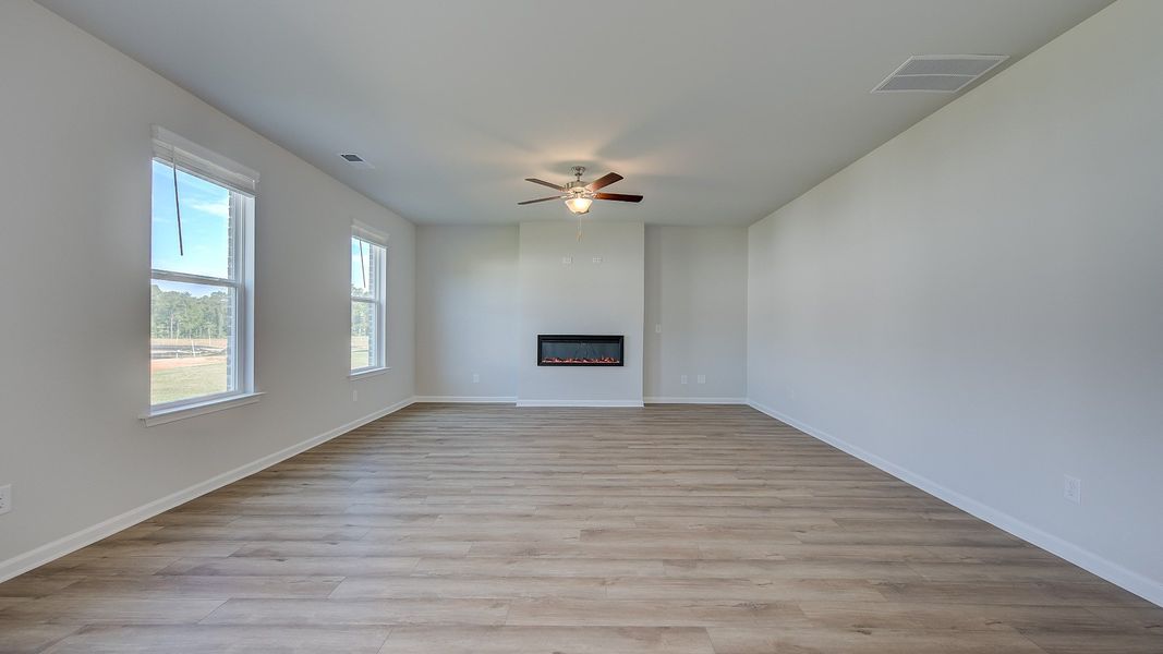 Expansive family room with LVP flooring, natural light, electric gas fireplace in the Ridgewood at Bowers Farm.