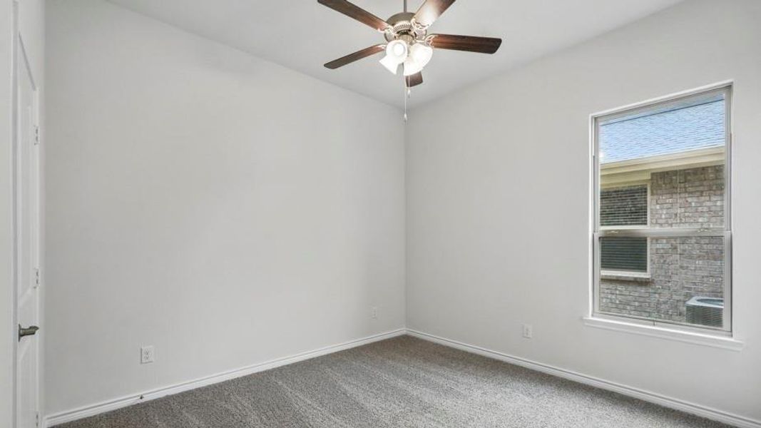 Interior room featuring light-colored walls, grey carpeting, a ceiling fan with integrated lighting, and a white-framed window
