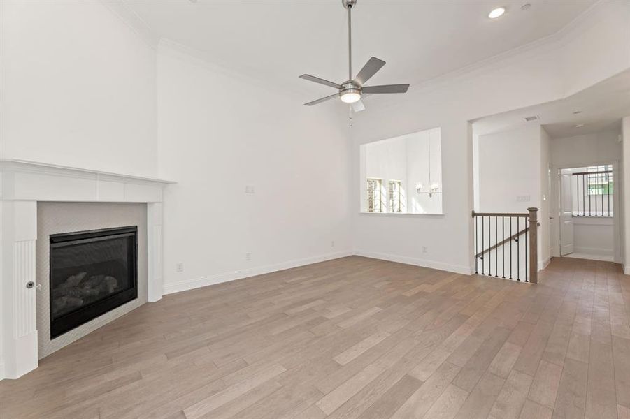 Unfurnished living room with light hardwood / wood-style floors, ornamental molding, and ceiling fan