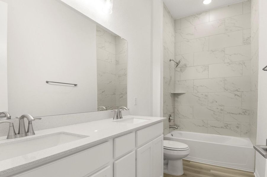 Bathroom featuring  shower combination, double vanity, and light wood-type flooring