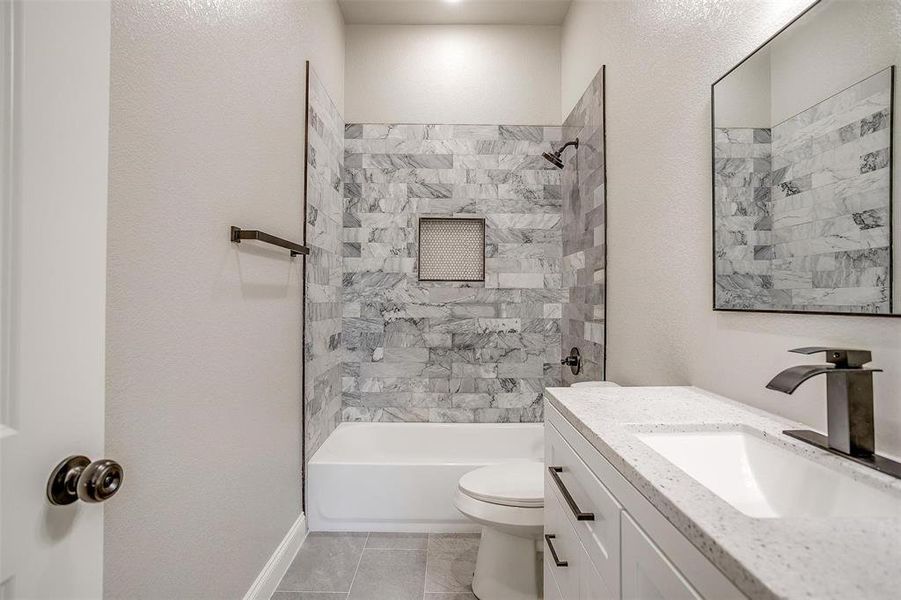 Full bathroom featuring washtub / shower combination, tile patterned flooring, vanity, toilet, and baseboards Full bathroom featuring washtub / shower combination, tile patterned flooring, vanity, toilet, and baseboards