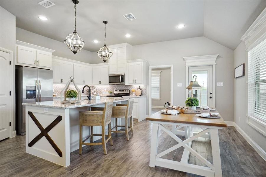 Kitchen featuring dark hardwood / wood-style floors, appliances with stainless steel finishes, white cabinets, an island with sink, and tasteful backsplash