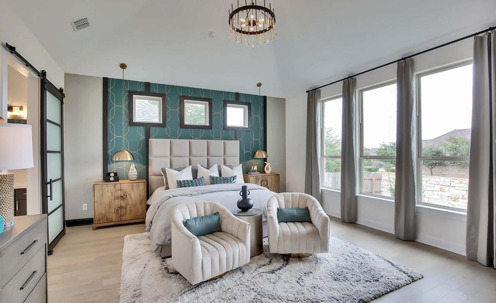 Bedroom featuring an accent wall, a barn door, light wood finished floors, a chandelier, and lofted ceiling