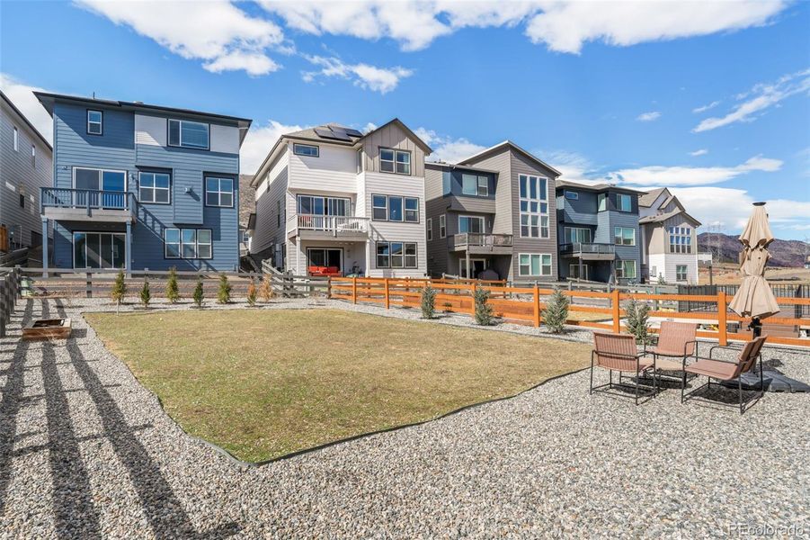 Expansive, fully landscaped backyard with open space, seating area, and fencing, offering a private, park-like setting in the Three Hills neighborhood of Morrison Colorado