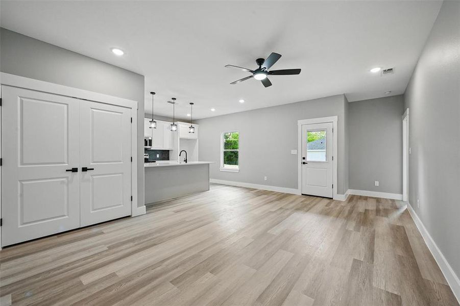 Unfurnished living room featuring ceiling fan, light wood-style flooring, baseboards, recessed lighting, and a sink