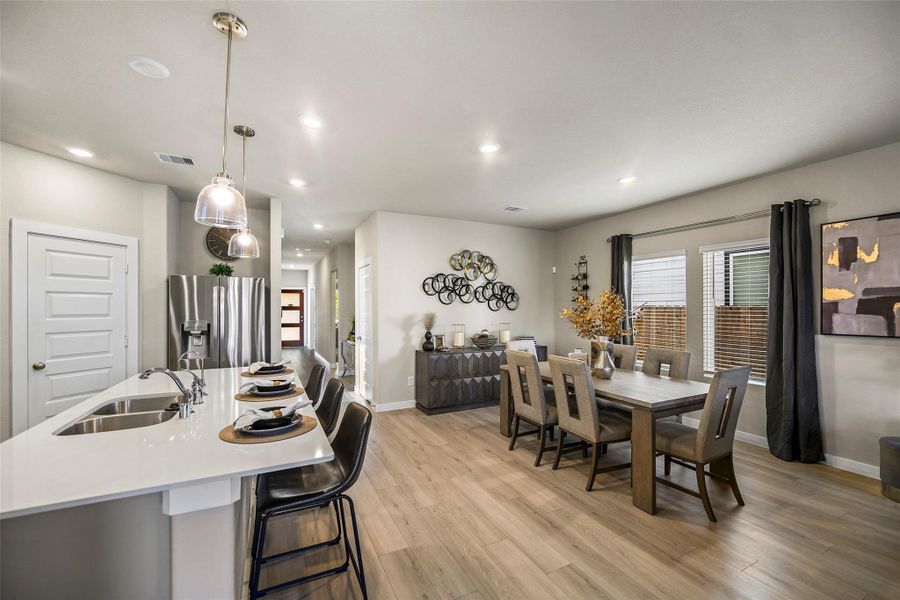 Bright and inviting open-concept living space featuring a modern kitchen with a breakfast bar, adjacent dining area, and stylish decor, perfect for entertaining.