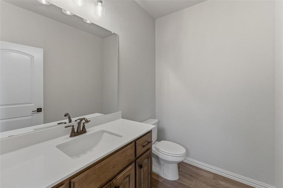 Bathroom featuring wood-finish flooring and a white vanity with a rectangular integrated sink