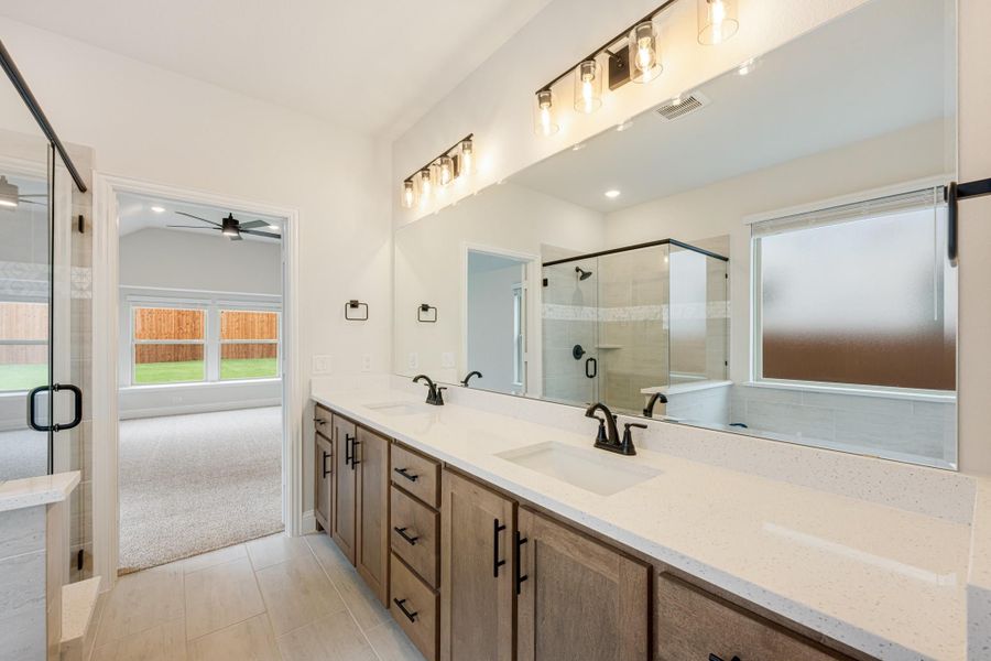 Master bathroom with double vanity, wood cabinets, quartz countertop, large mirror, and glass shower enclosure. Master bathroom with double vanity, wood cabinets, quartz countertop, large mirror, and glass shower enclosure.