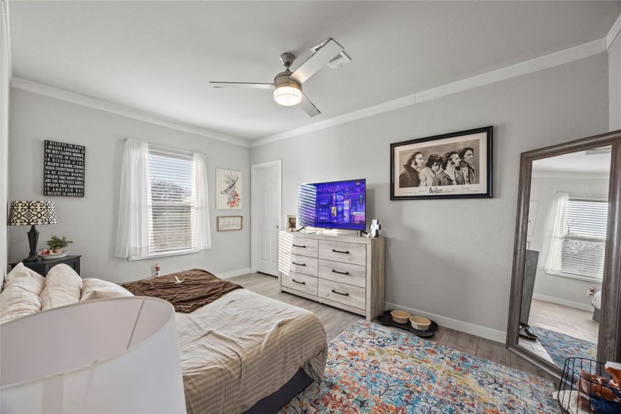 Bedroom with ornamental molding, a ceiling fan, and wood finished floors