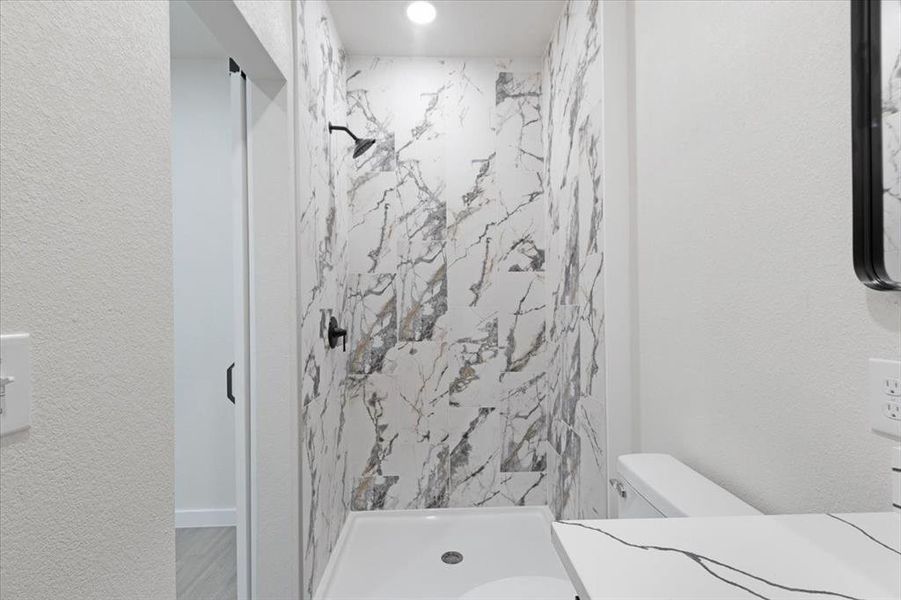 Bathroom featuring a tile shower, hardwood / wood-style flooring, and toilet