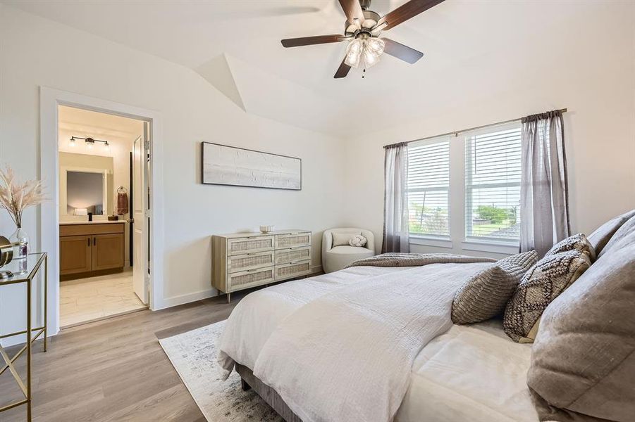 Bedroom with light wood-style flooring, a ceiling fan, lofted ceiling, and connected bathroom