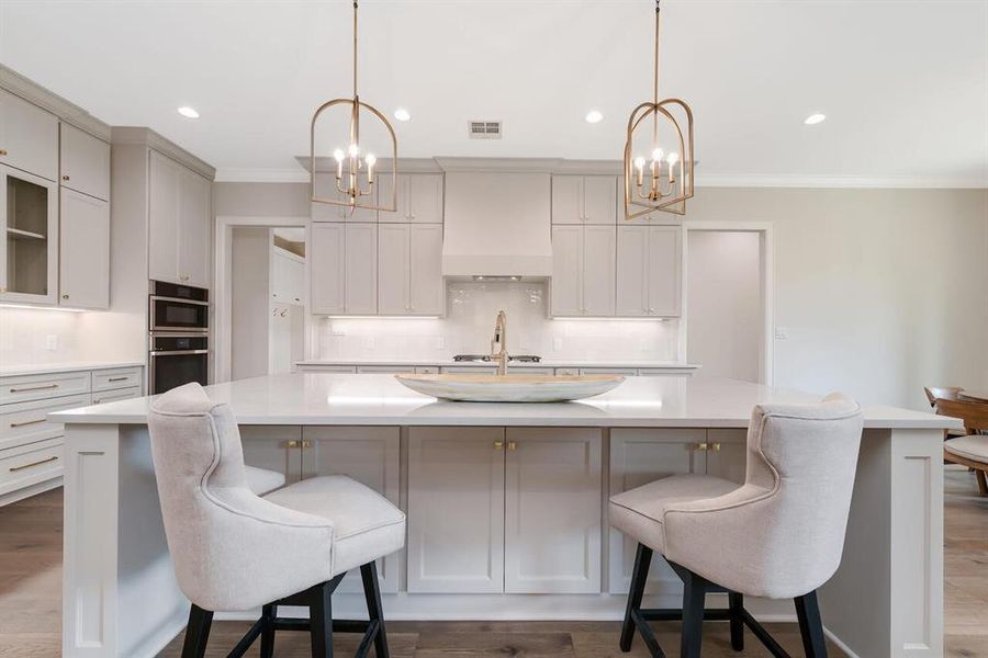 Kitchen featuring a chandelier, ornamental molding, a large island, light countertops, and decorative backsplash Kitchen featuring a chandelier, ornamental molding, a large island, light countertops, and decorative backsplash