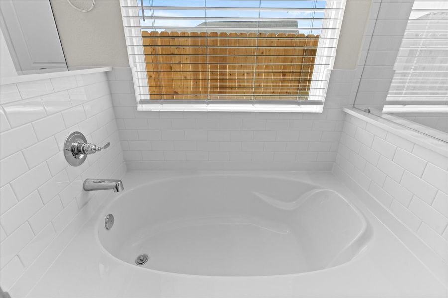 Relaxing soaking tub perfectly positioned beneath a window that allows natural light to fill the space. This spa inspired feature creates the perfect place to unwind after a long day while adding charm and comfort to the primary bathroom.