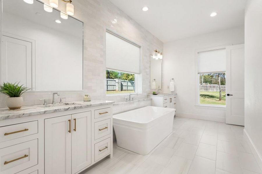 Full bathroom featuring a soaking tub, recessed lighting, two vanities, decorative backsplash, and light tile patterned flooring