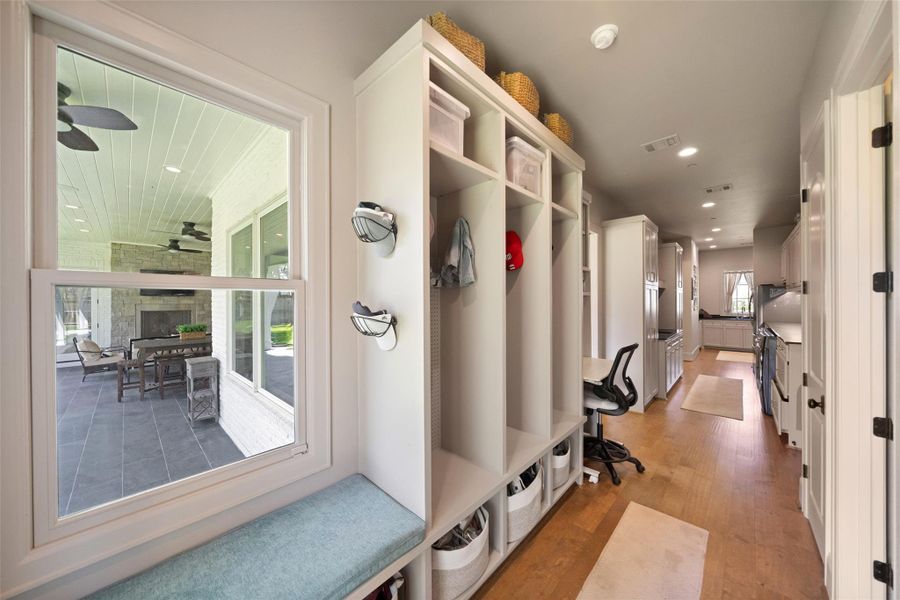 This additional view of the mudroom and utility room highlights a large built-in bench for seating, paired with a generous window that overlooks the backyard.