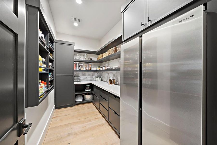 Just off the chefs kitchen This luxury working walk-in pantry offers built in drawers, floating shelves, cabinets, and second full-size fridge, designer style backsplash, and quartz countertops.