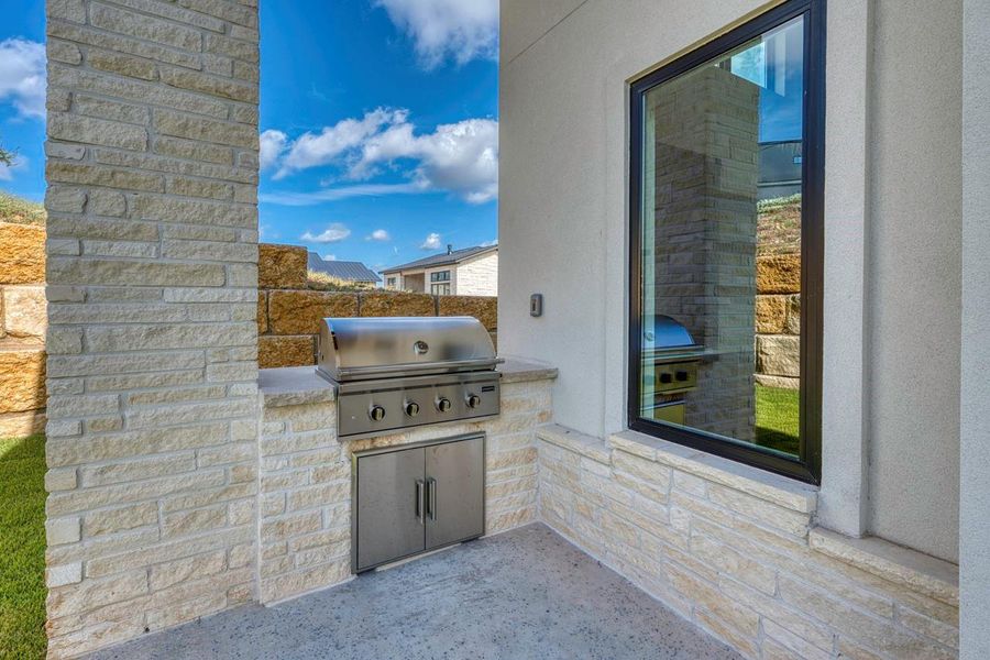 An outdoor grilling station built into stone walls under a covered patio. An outdoor grilling station built into stone walls under a covered patio.