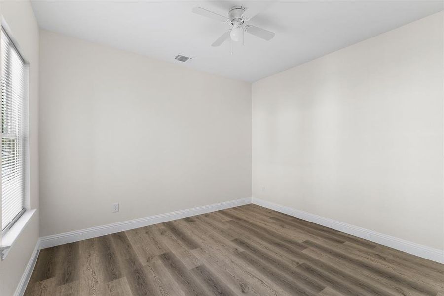 Unfurnished room with a healthy amount of sunlight, dark wood-type flooring, and ceiling fan