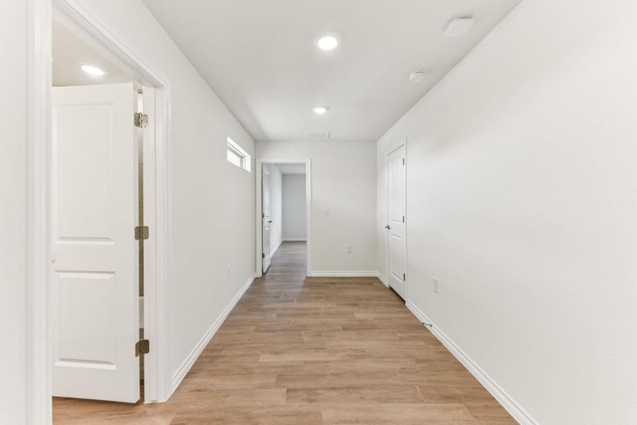 Hallway with light wood finished floors and recessed lighting Hallway with light wood finished floors and recessed lighting