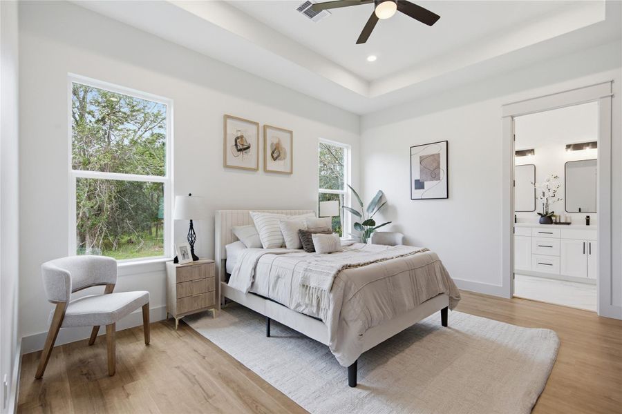 Natural light floods this spacious bedroom, featuring warm hardwood flooring and an elegant tray ceiling. Natural light floods this spacious bedroom, featuring warm hardwood flooring and an elegant tray ceiling.