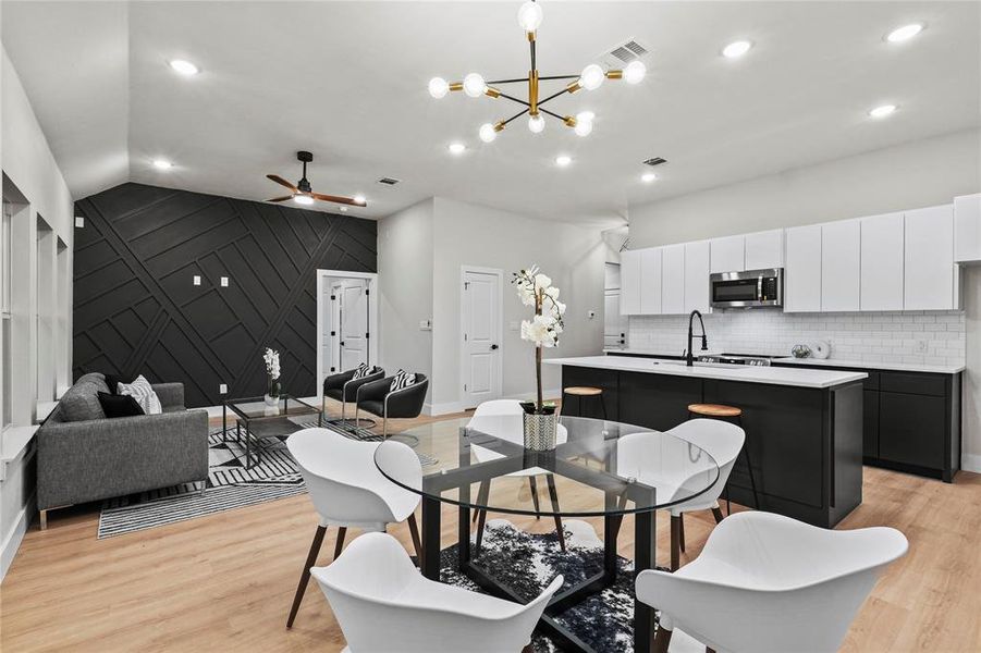 Dining area featuring ceiling fan with notable chandelier, light hardwood / wood-style flooring, lofted ceiling, and sink