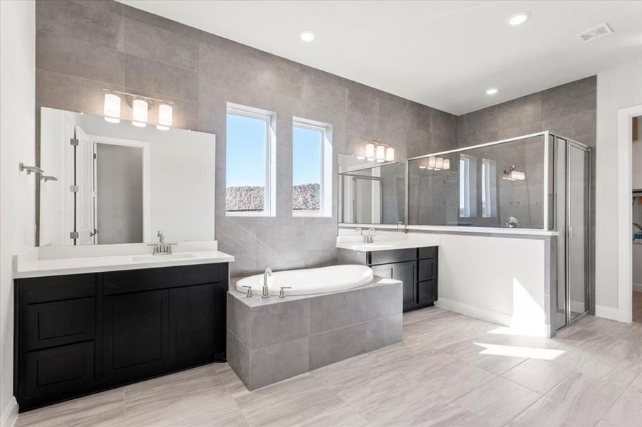 Bathroom featuring a stall shower, a bath, two vanities, a spacious closet, and recessed lighting