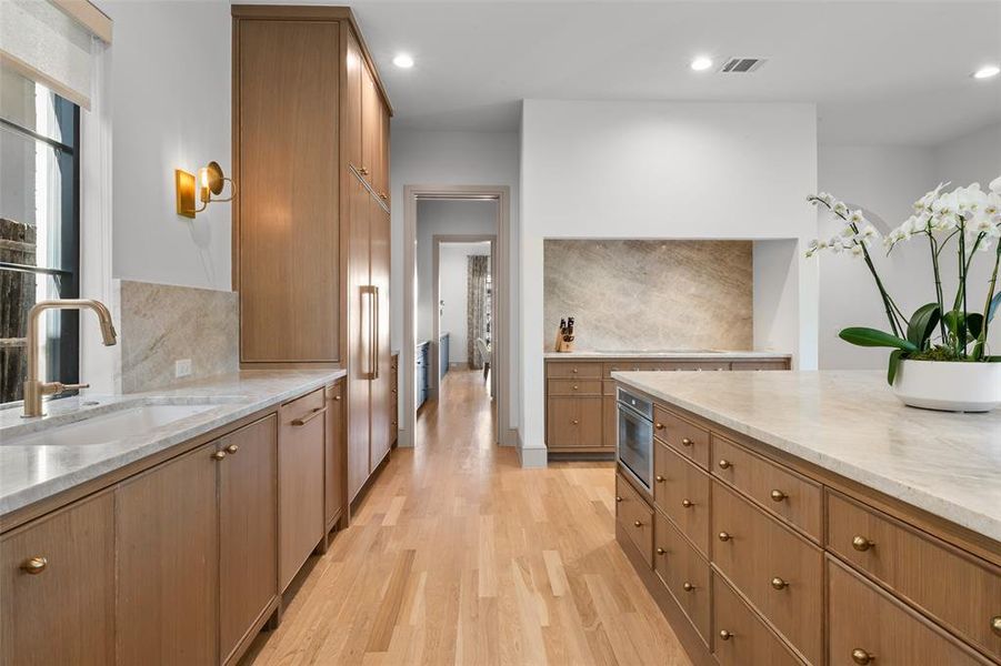 Kitchen featuring quartzite counters and backsplash, rift cut white oak cabinetry, wood floors