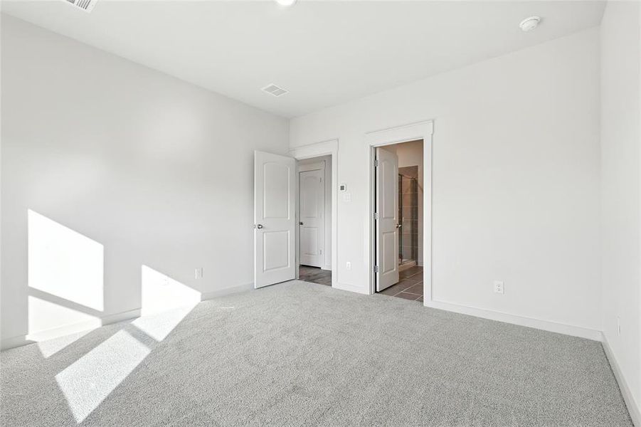 Unfurnished bedroom with carpet floors and connected bathroom Unfurnished bedroom with carpet floors and connected bathroom