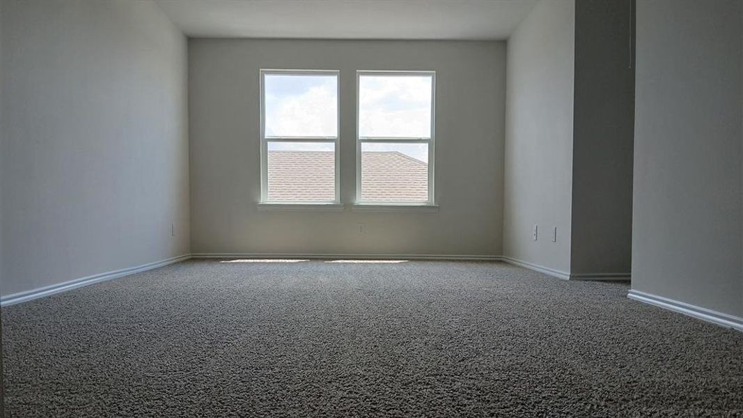 Spacious room featuring neutral carpeting, light-toned walls, and white baseboards Spacious room featuring neutral carpeting, light-toned walls, and white baseboards