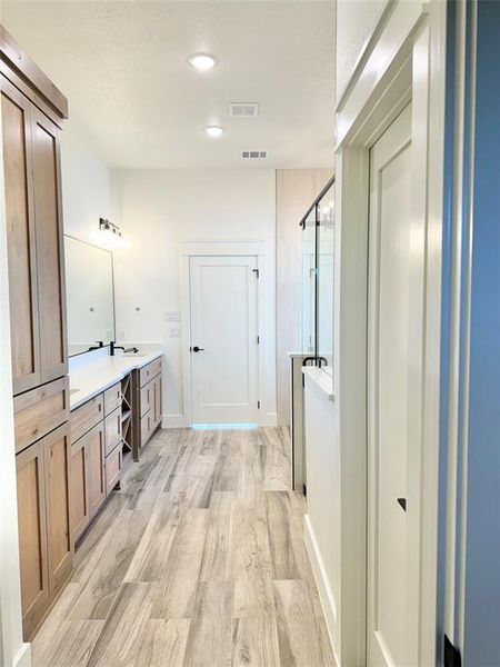 Bathroom with a stall shower, visible vents, vanity, and wood finished floors