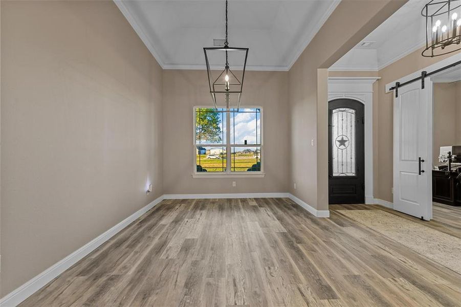 Entrance foyer featuring a barn door, crown molding, hardwood / wood-style floors, and a chandelier